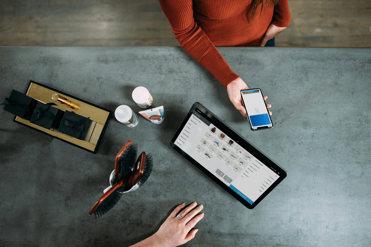 Person paying with a smartphone next to a tablet computer